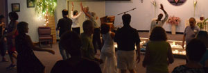 People dancing together in a dimly lit room with a piano in the background.