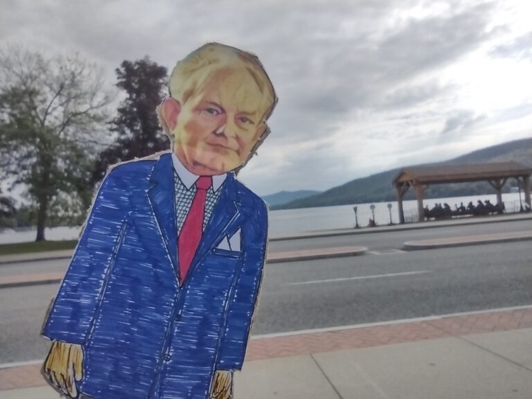 paper doll in front of road with lake
