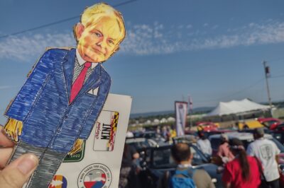 person holding paper doll with stickers against a blue sky