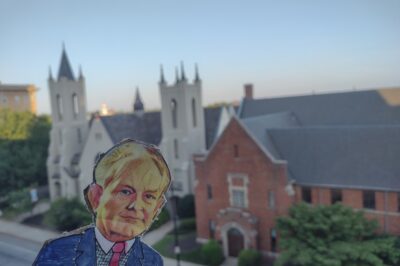 paper doll in front of cathedral and blue sky