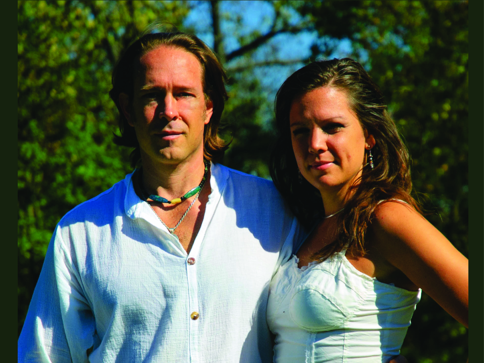 A man and woman standing outdoors in casual white shirts.