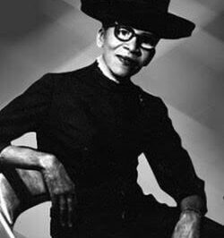 Black and white portrait of a woman in glasses and a hat.