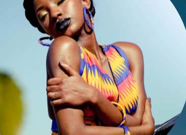 Confident woman posing outdoors in colorful attire under clear blue sky.