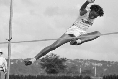 Athlete performing a high jump in mid-air over the bar.