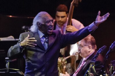 Two musicians passionately performing on stage with a jazz band.