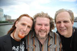 Three men smiling and posing closely for a photo.