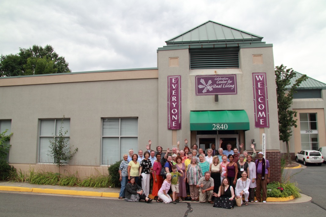 A large group poses outside a building with 'Welcome' signs.