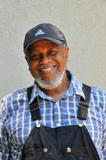 Smiling man wearing a cap and checkered shirt.