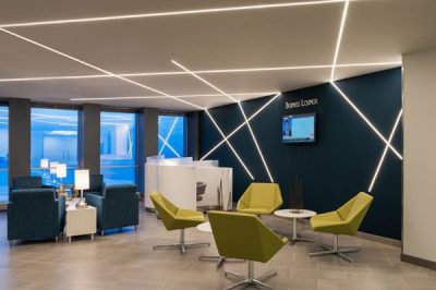 Modern office waiting area with green chairs and sleek lighting.