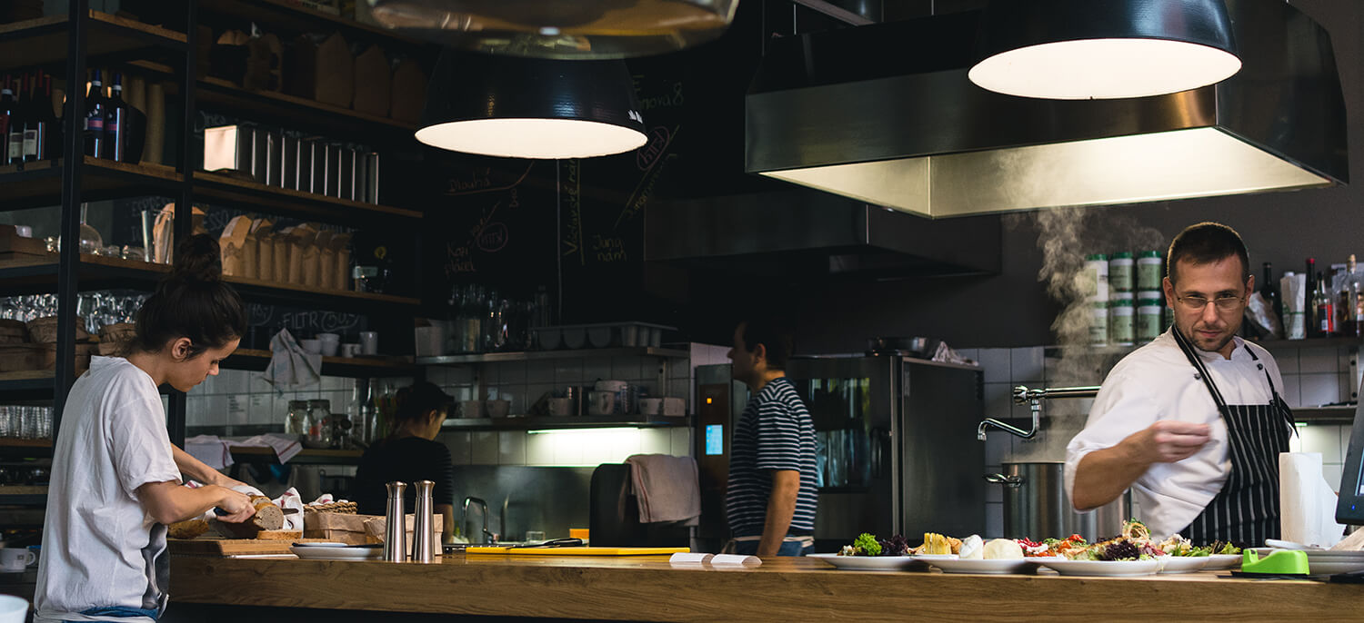 Two chefs working in a dimly lit commercial kitchen.