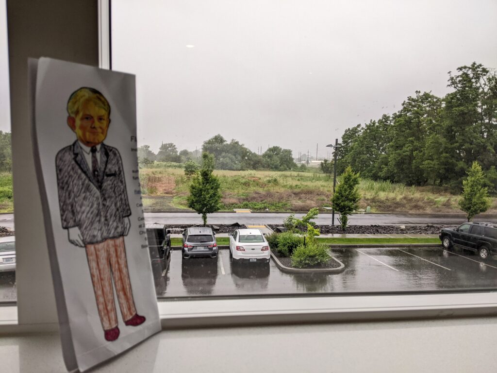paper doll in front of window with cars and highway