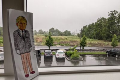 paper doll in front of window with cars and highway