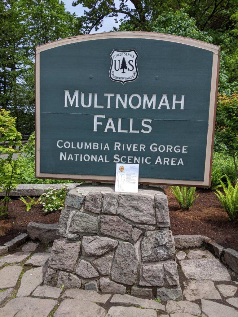 paper doll in front of Multnomah falls signage