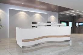 Modern white reception desk with curved design in a bright office.