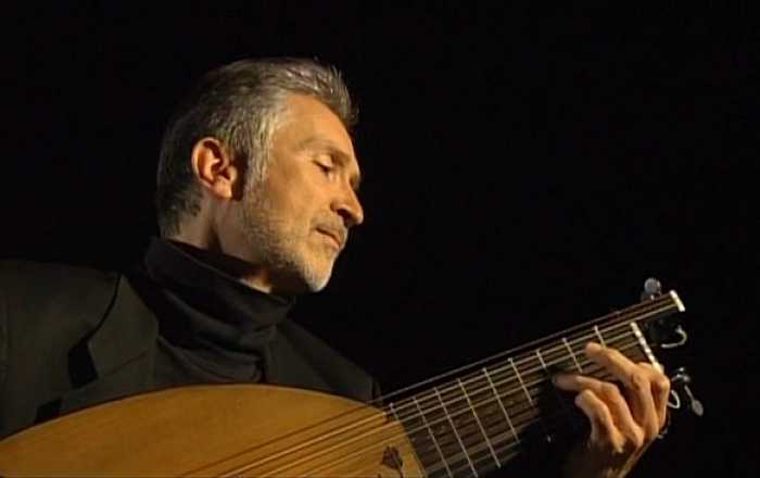 A man playing a string instrument with focus and passion.
